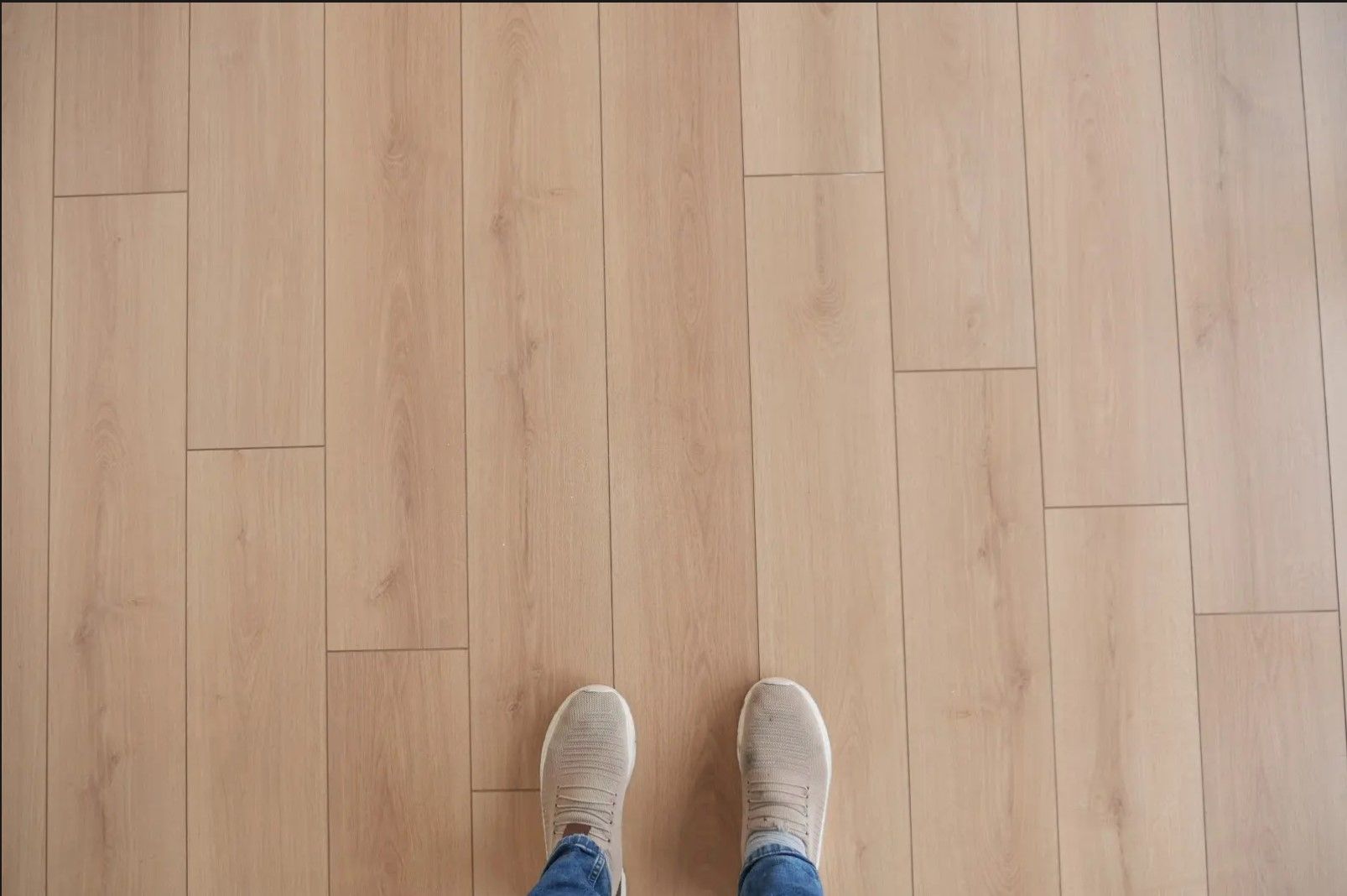 A person 's feet are standing on a wooden floor.