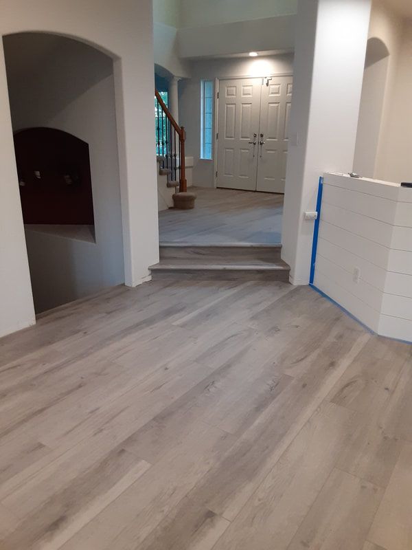A living room with a wooden floor and stairs.