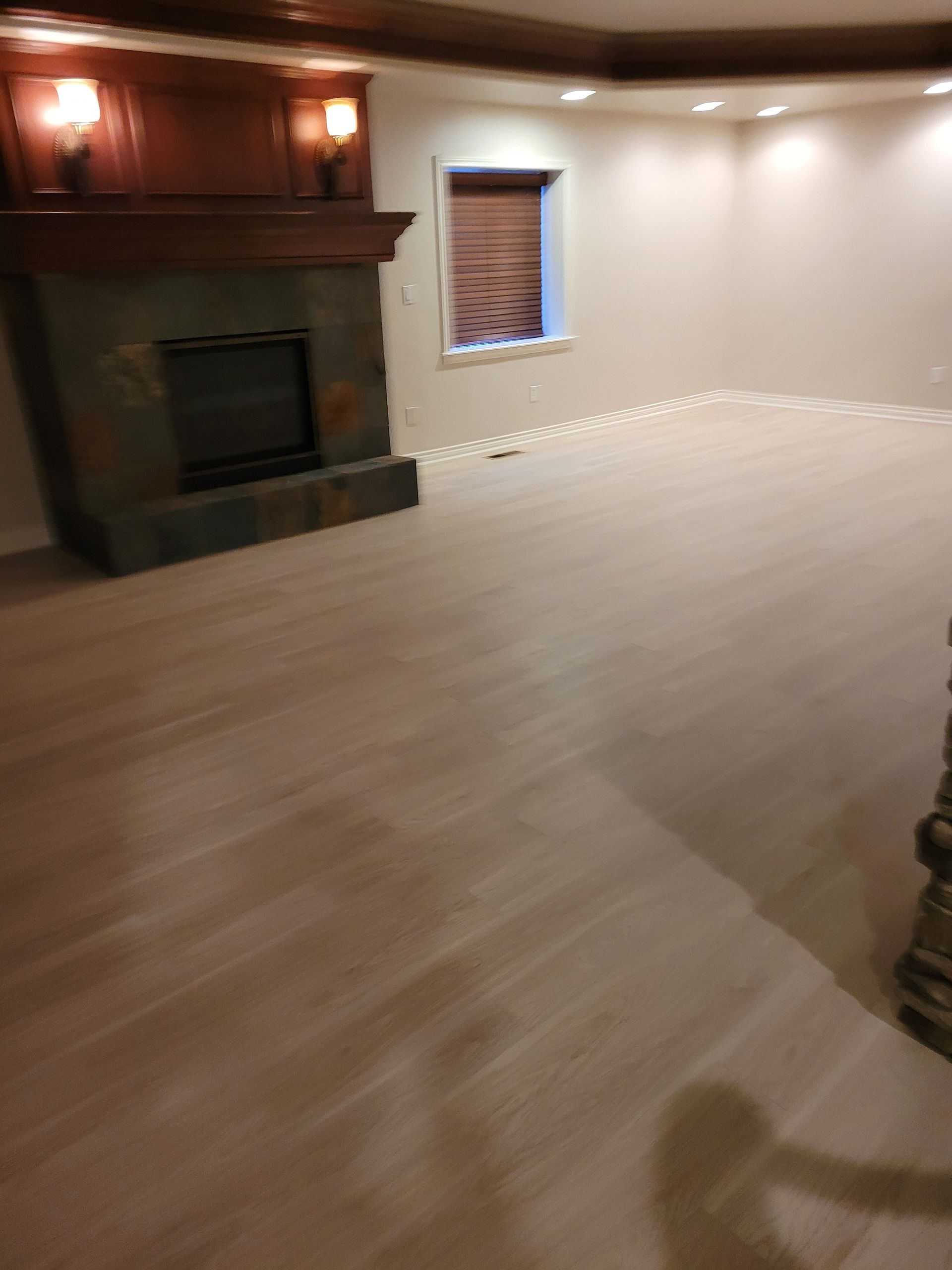 An empty living room with a fireplace and a window.