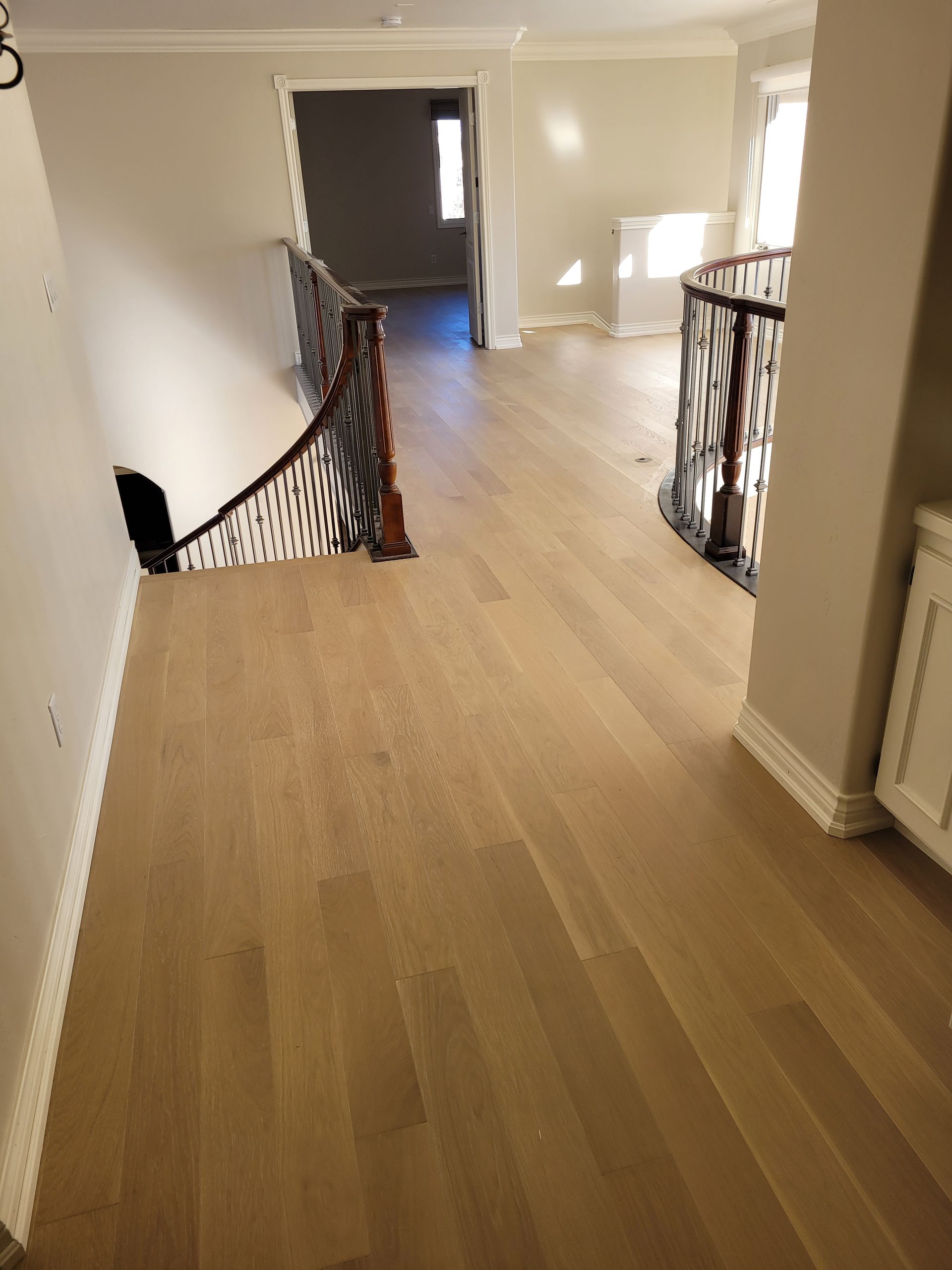 A hallway with wooden floors and stairs in a house.