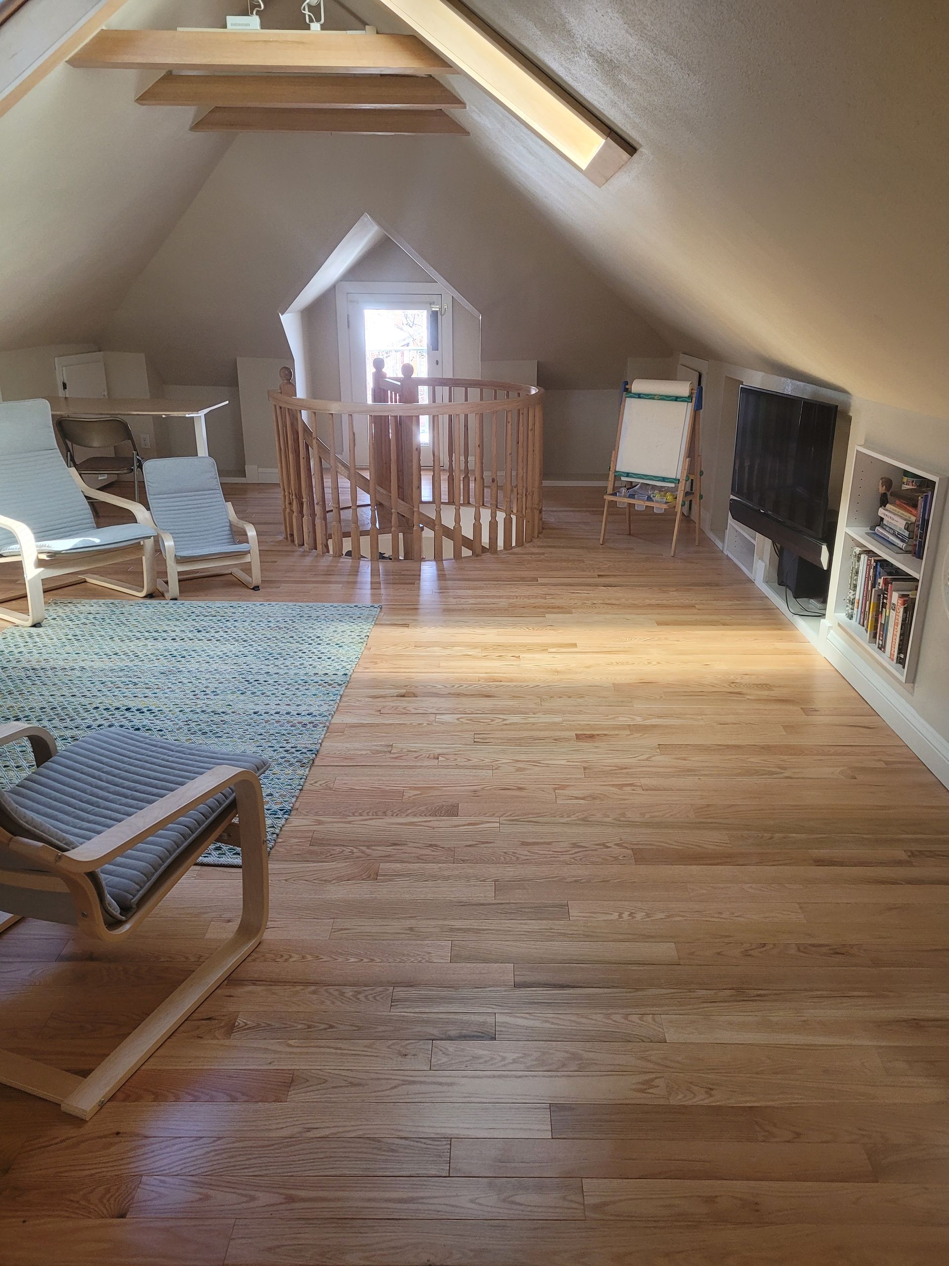 A living room with wooden floors , chairs , a staircase and a playhouse.