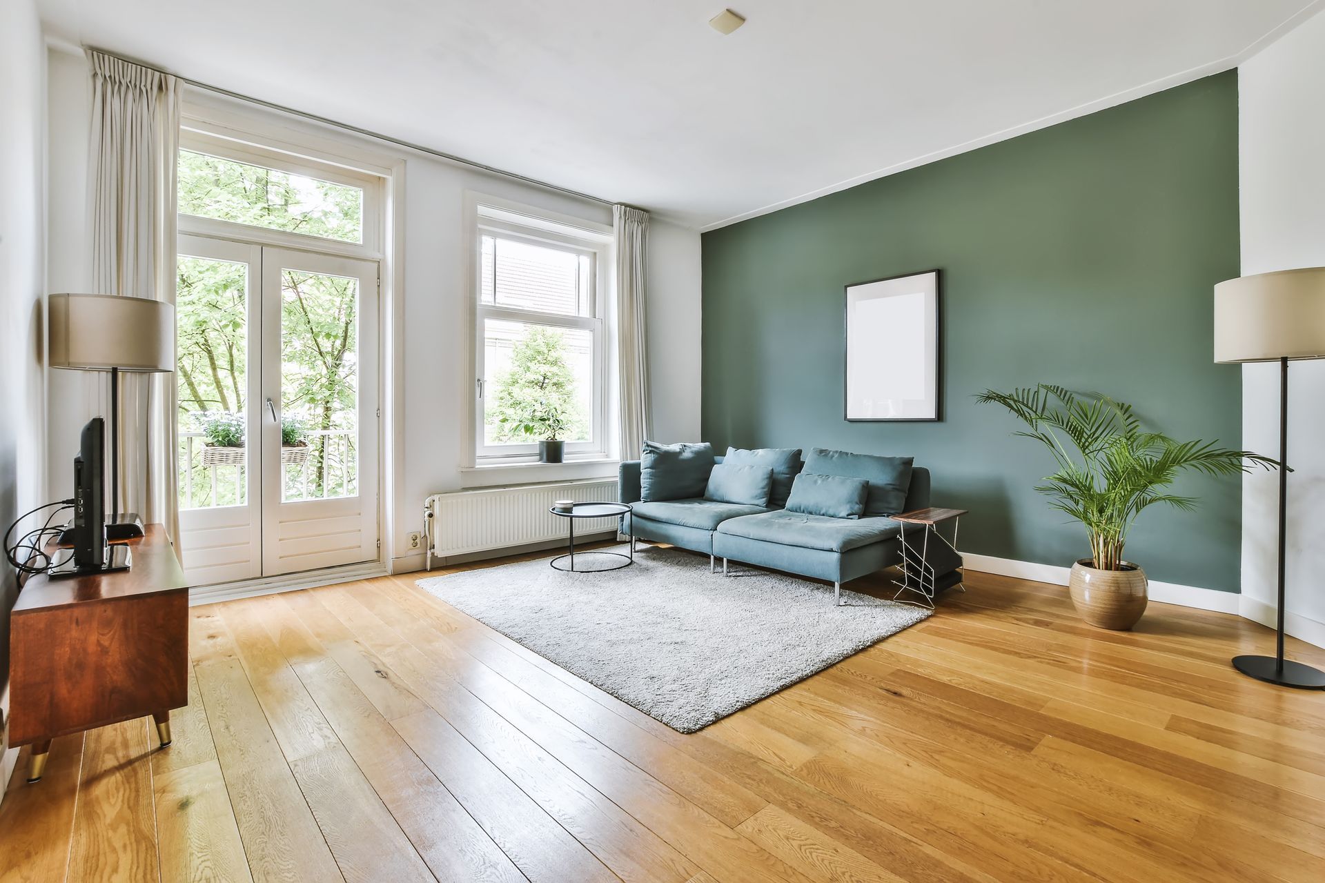 A living room with a couch , rug , television and green walls.