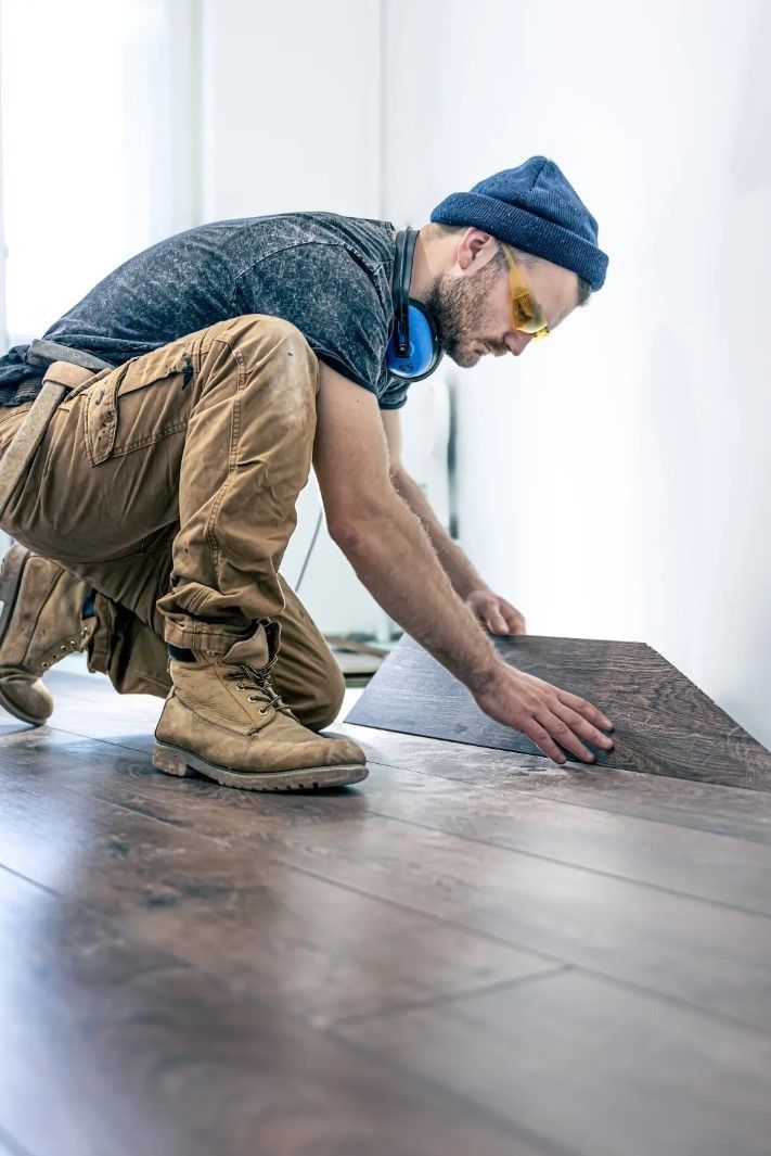 A man is installing a hardwood floor in a room.