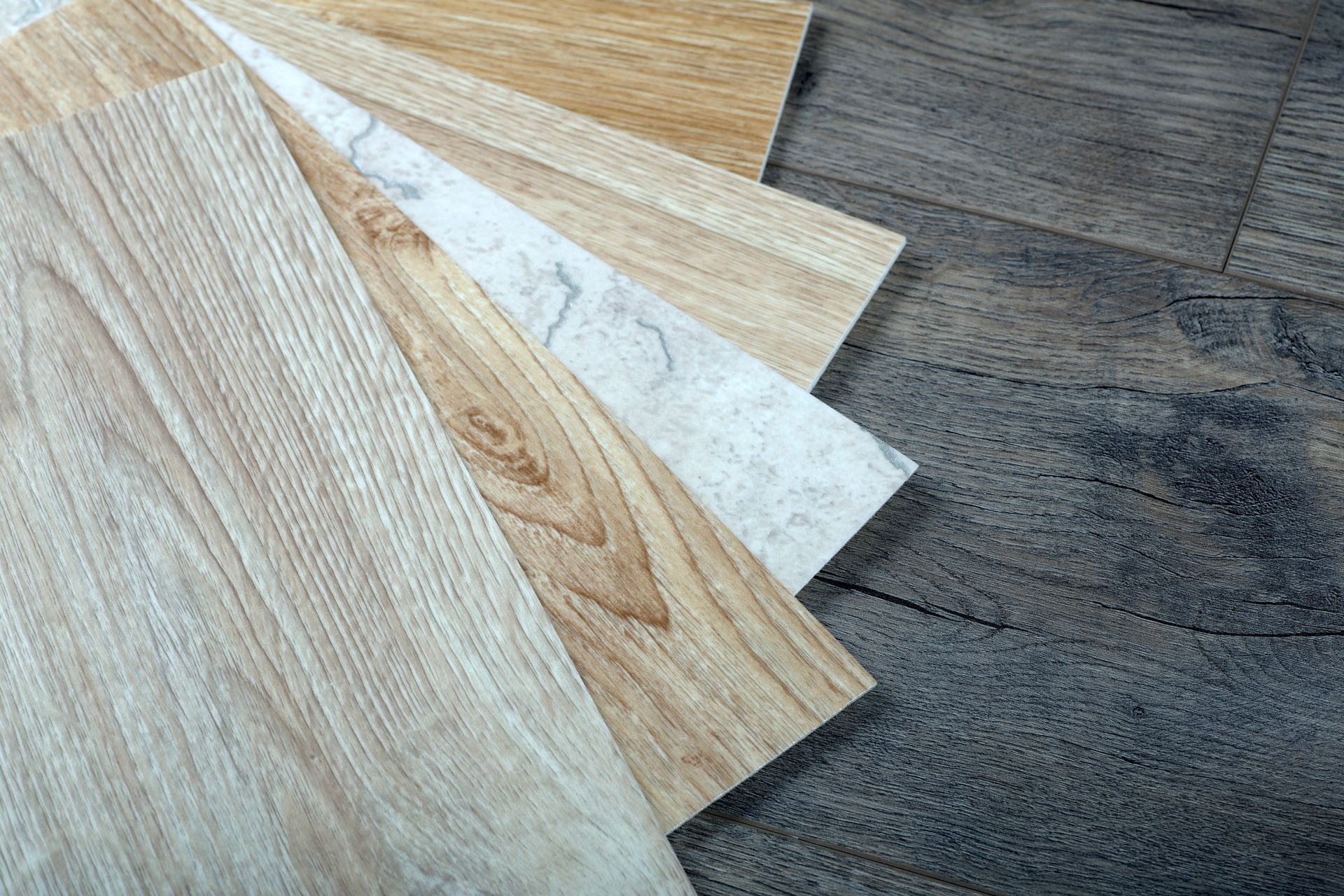 A variety of wooden flooring samples are stacked on top of each other on a wooden floor.