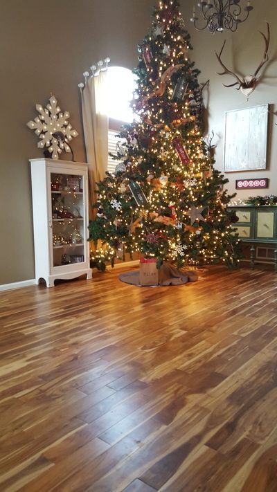 A living room with a christmas tree and a wooden floor.