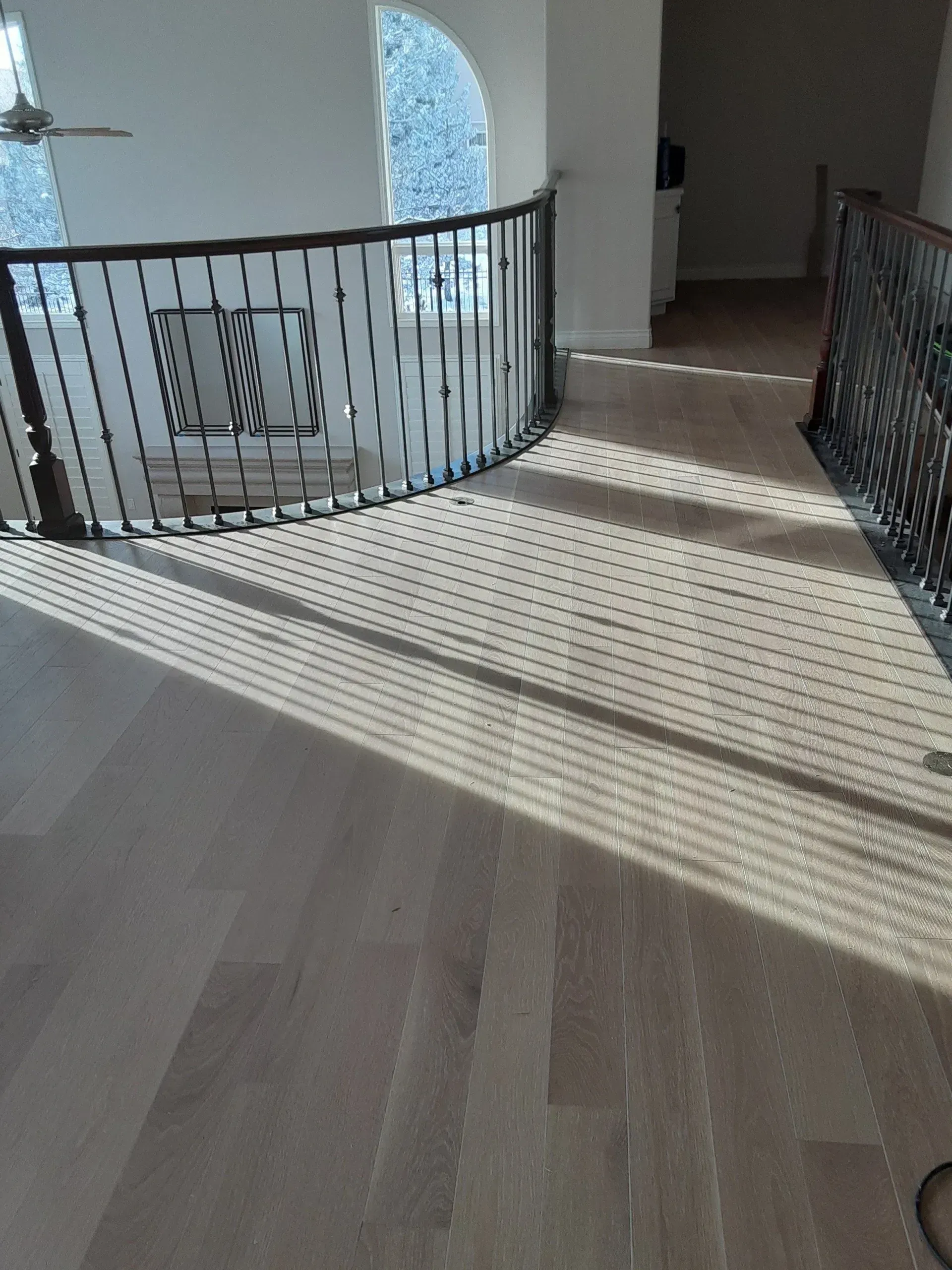 A room with hardwood floors and a wrought iron railing