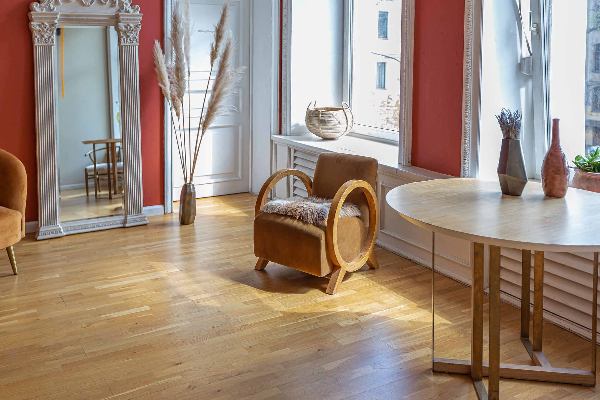 A living room with a chair , table , mirror and vases.