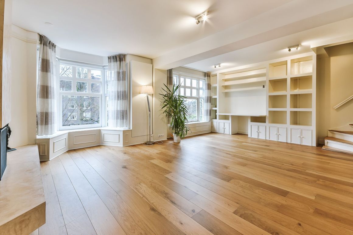 A large empty living room with hardwood floors and stairs.