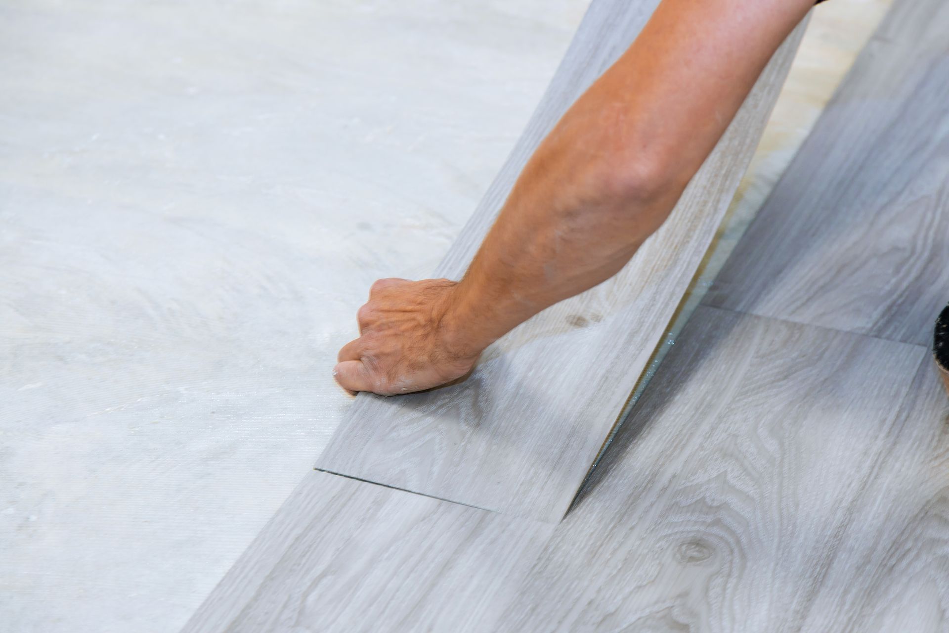 A person is laying a piece of vinyl flooring on the floor.