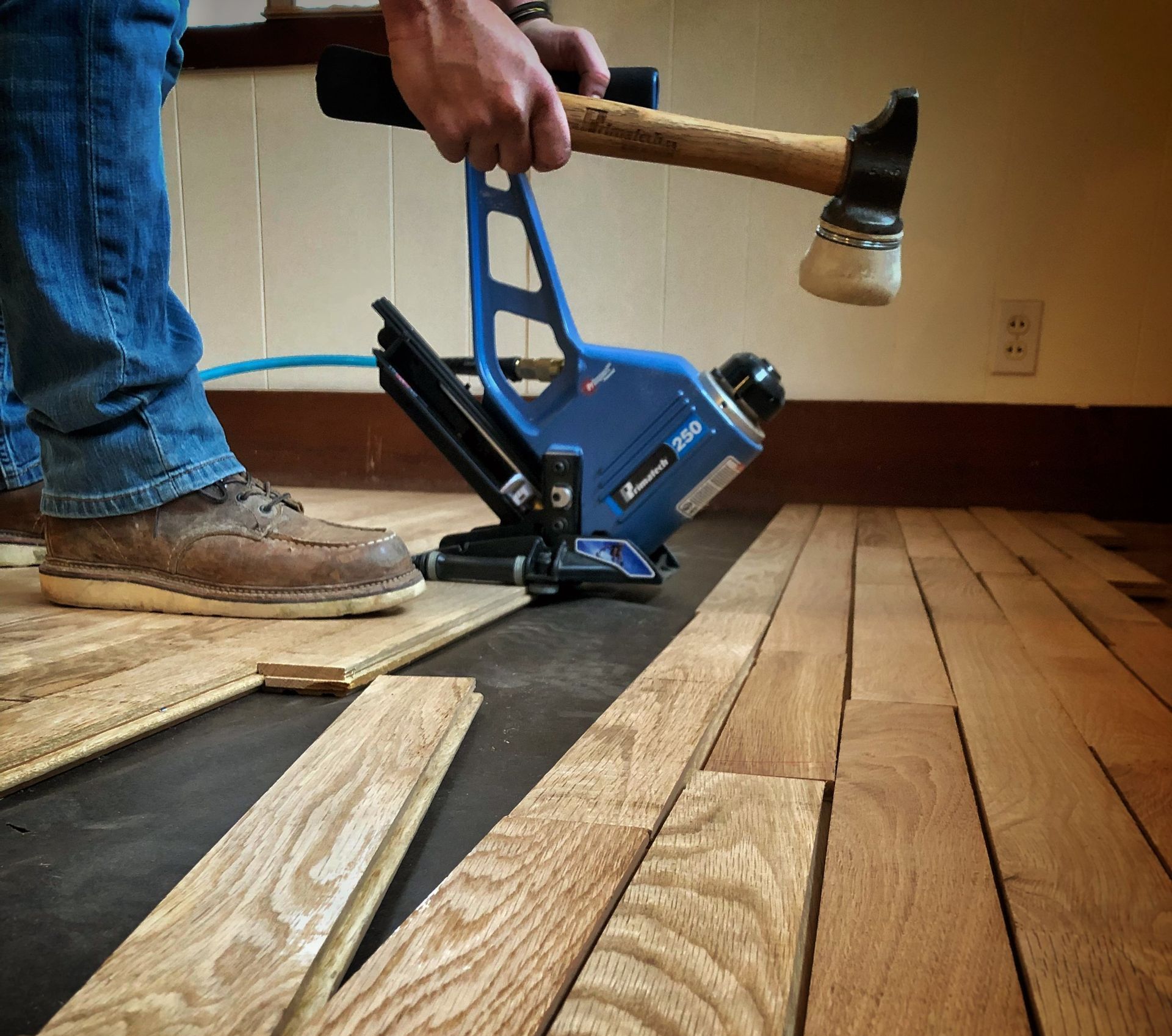 A person is holding a hammer over a wooden floor