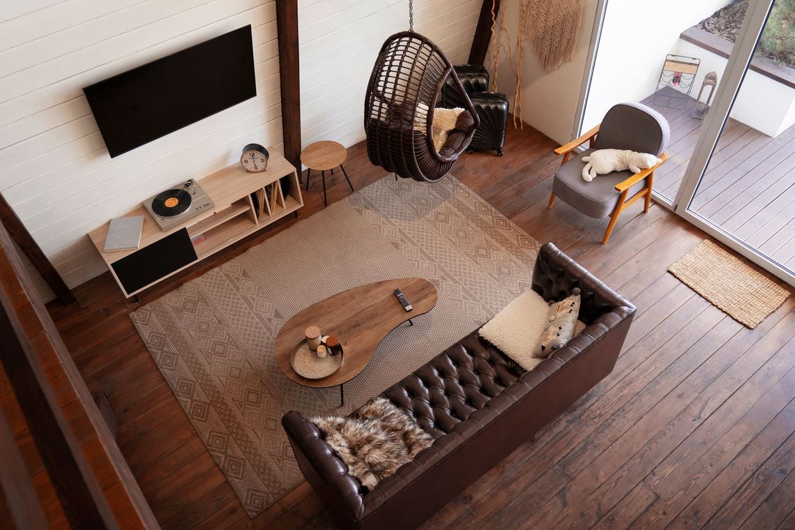 An aerial view of a living room with a couch , chair , coffee table and television.