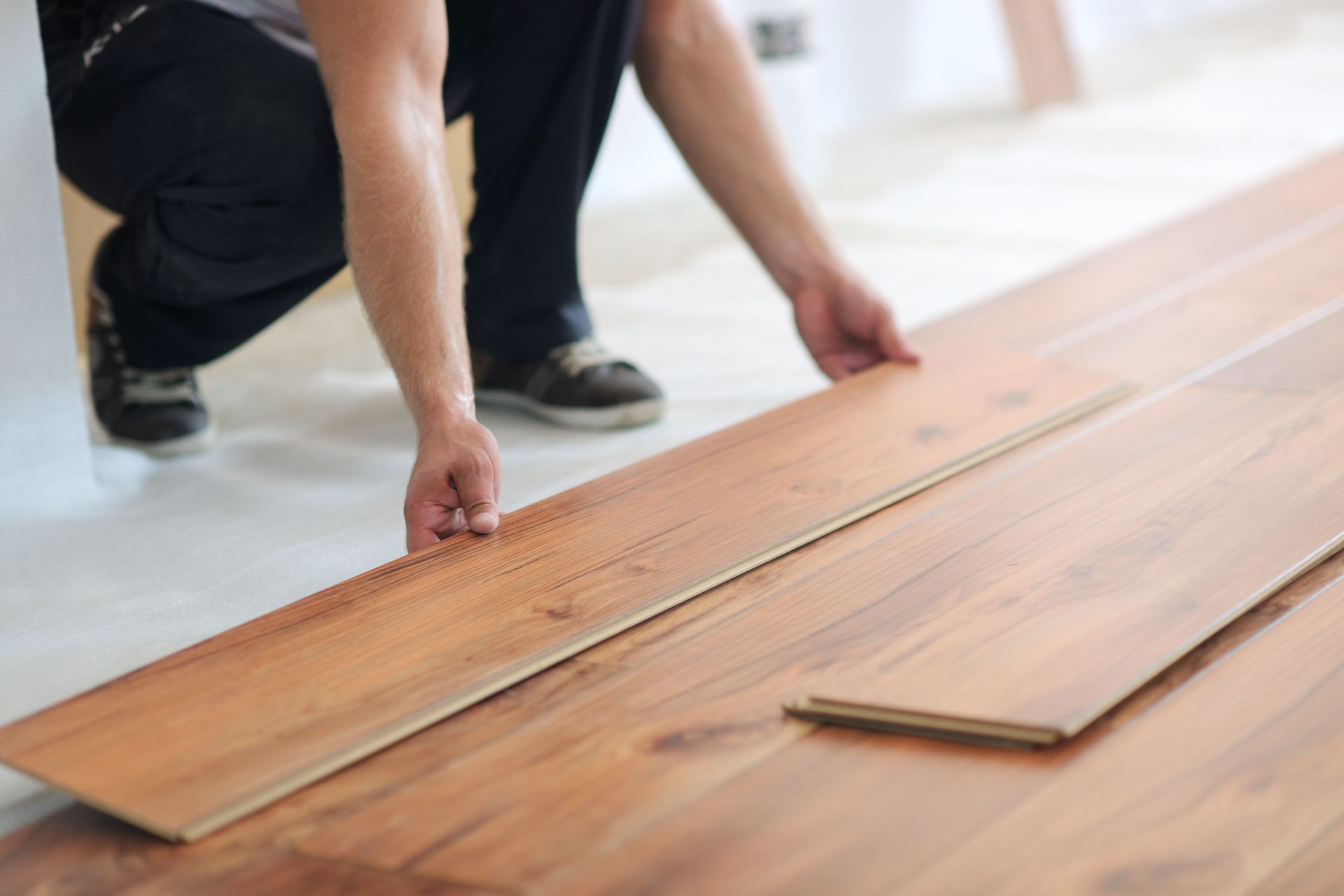 A man is installing a wooden floor in a room.