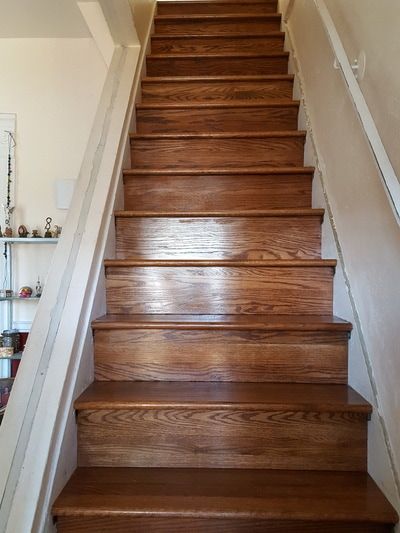A wooden staircase with a white railing in a house.