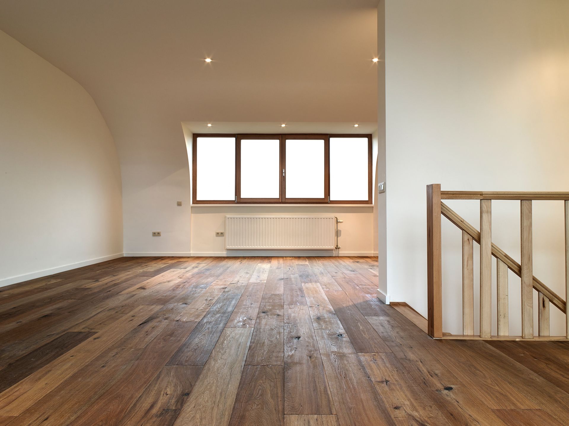 An empty room with a wooden floor and stairs.