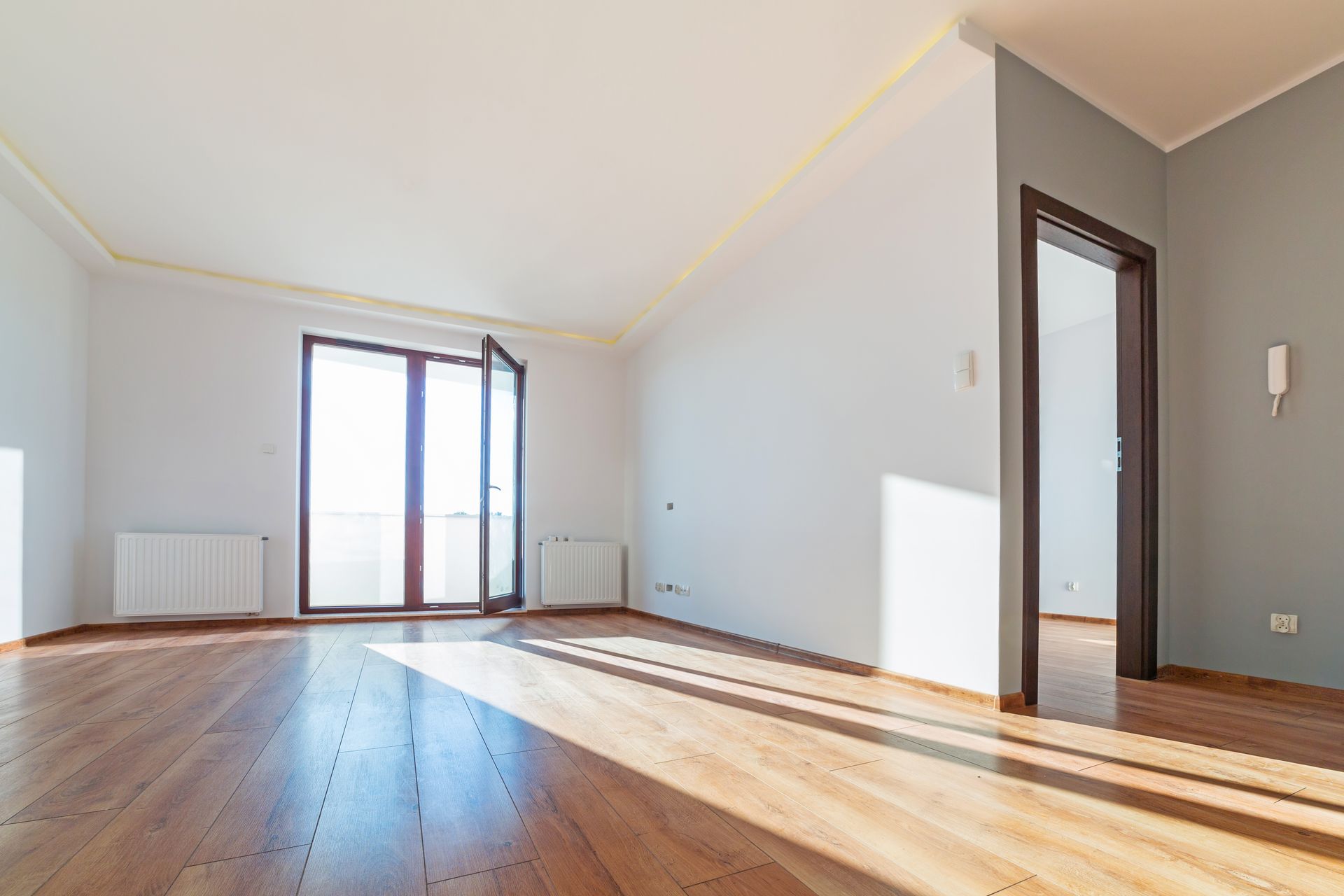 An empty living room with hardwood floors and white walls.