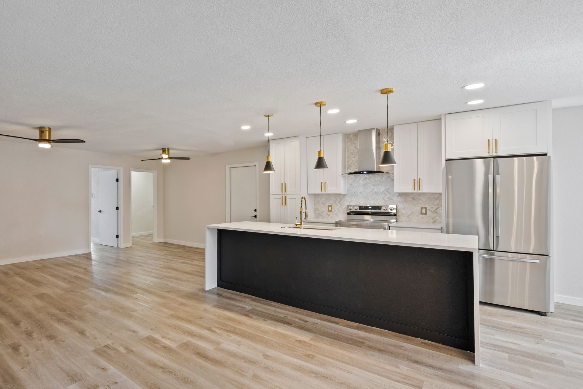 An empty kitchen with stainless steel appliances and a large island.