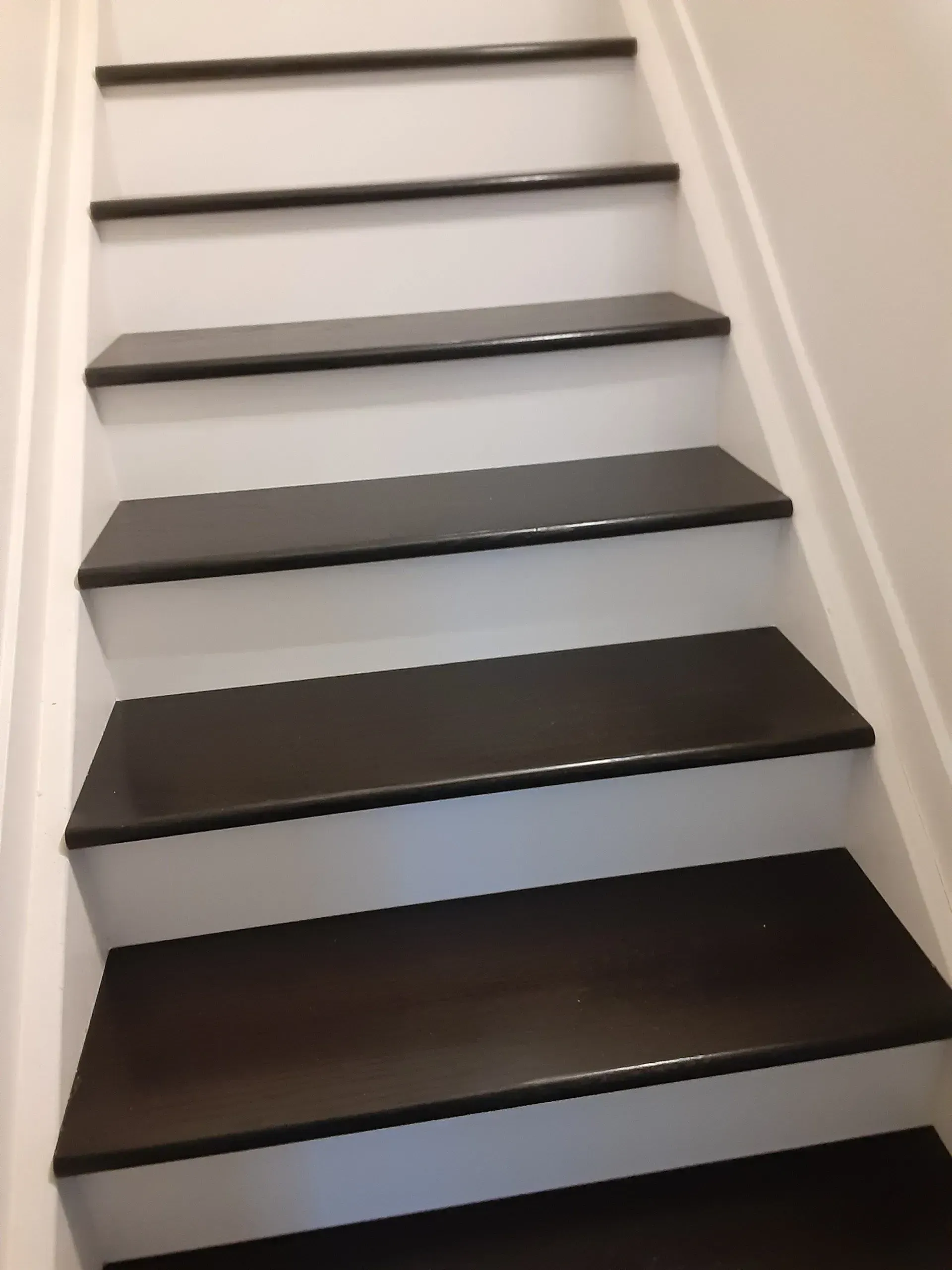 A set of stairs with black steps and white railing