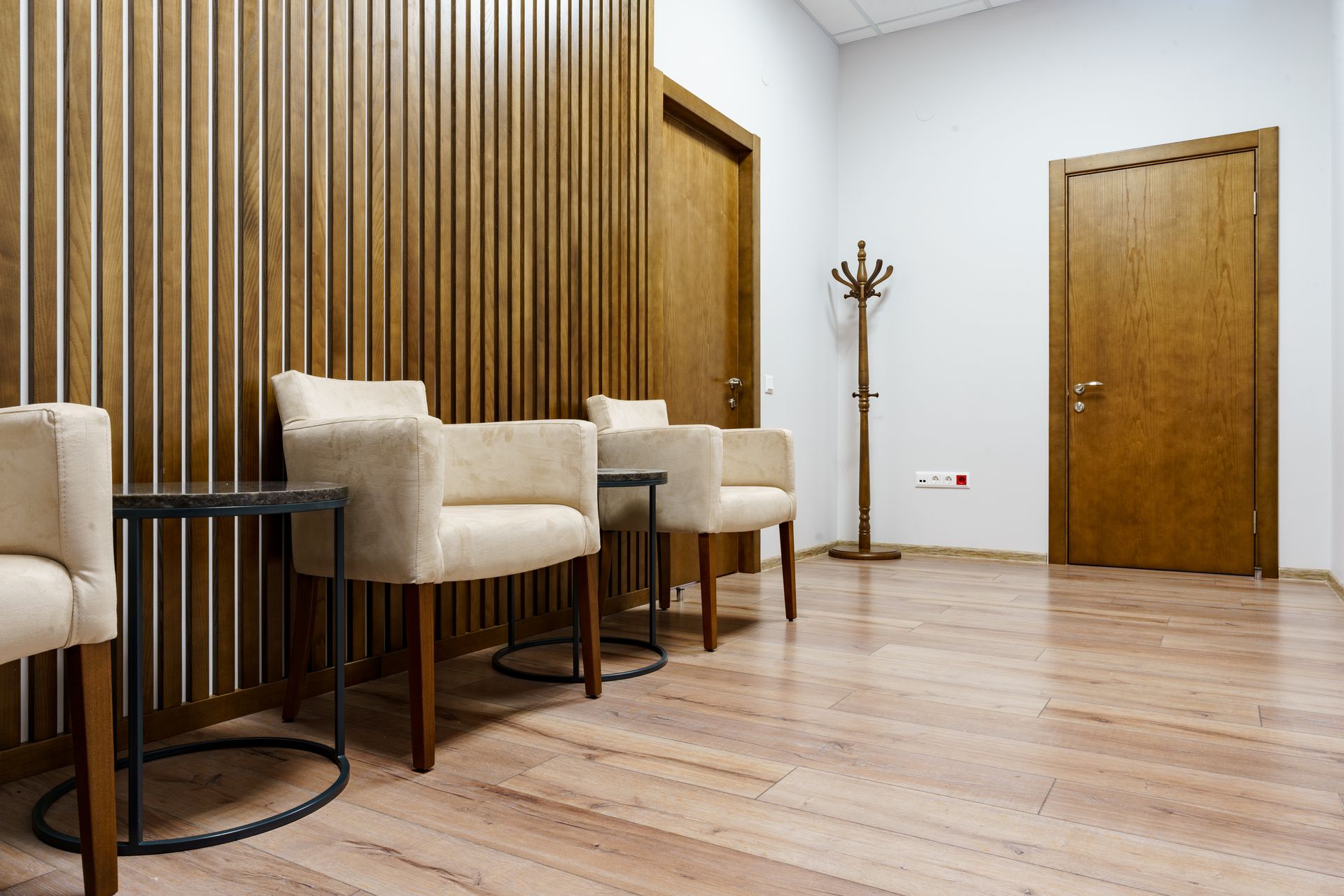 A waiting room with chairs , tables and a coat rack.