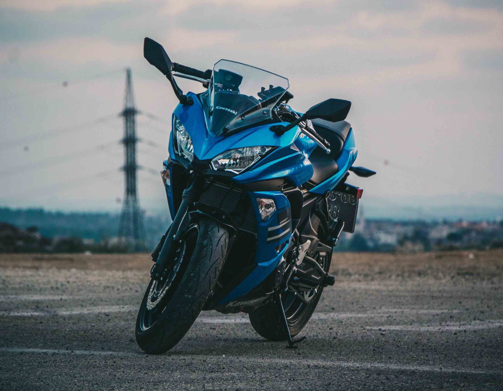 Blue sport motorcycle parked on pavement; power lines in background.