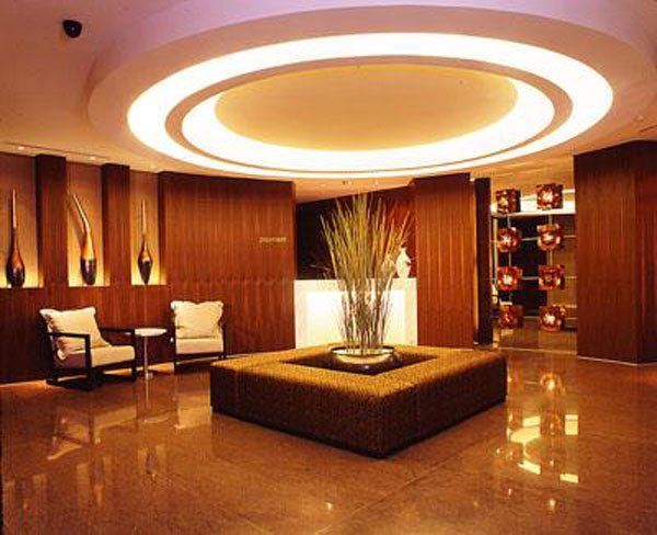 Lobby with brown wood paneling, seating, and a large decorative planter in the center, lit by a round ceiling fixture.