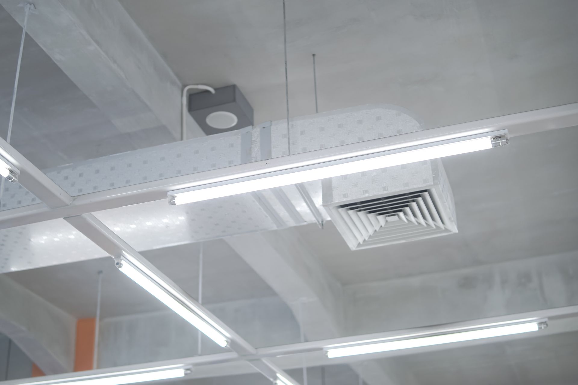 Gray ceiling with air ducts, fluorescent lights, and a vent.
