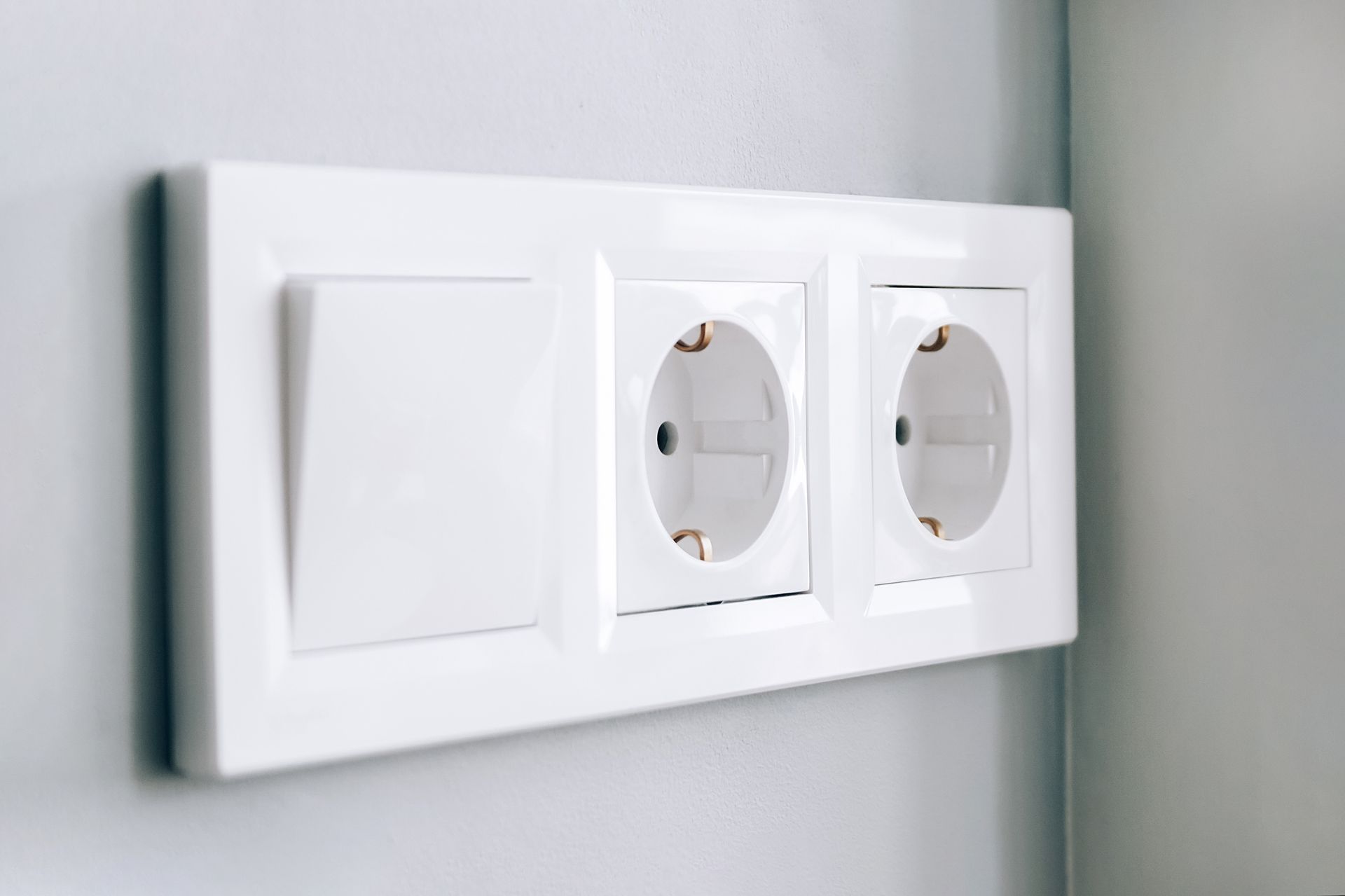 White electrical outlet and light switch on a gray wall.