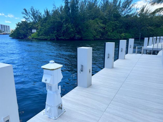 Electrician installing an outlet with tools, wires, and gloves on a white wall.