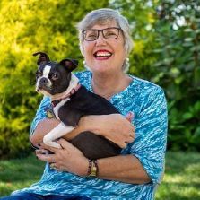 A woman is holding a small black and white dog in her arms.