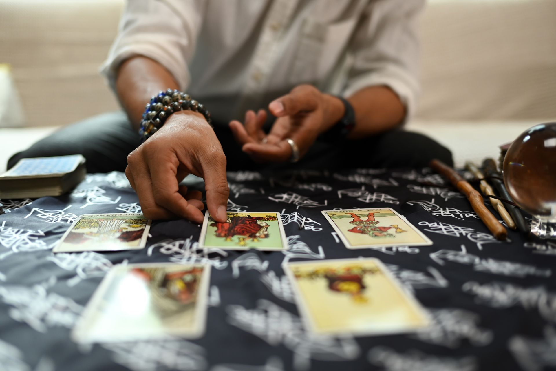 A man is sitting at a table playing tarot cards.