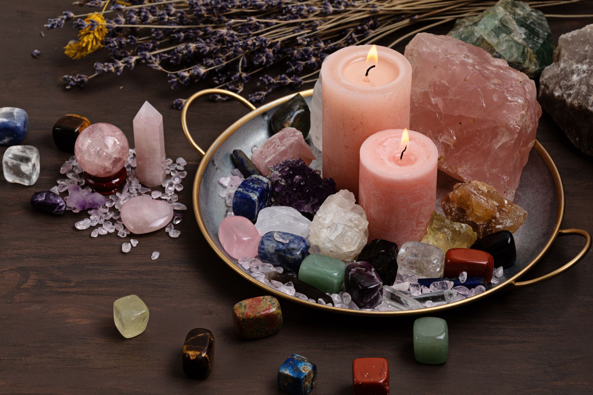 Crystals and candles on a tray with dried lavender, a soft, spiritual scene.