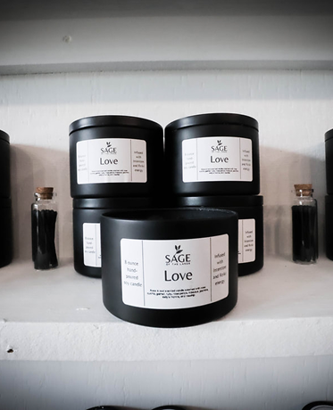 Four black candles are stacked on top of each other on a shelf.