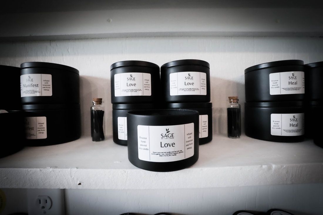 A shelf filled with black jars of candles and bottles.