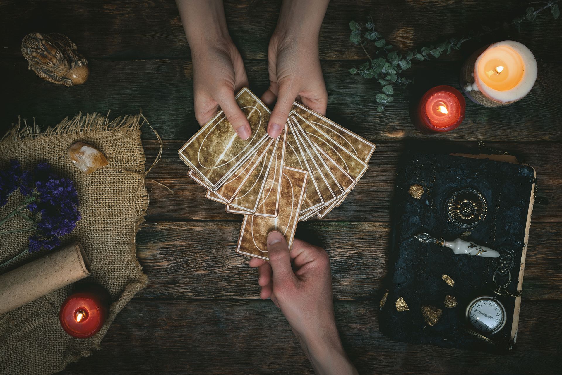 Two people are playing tarot cards on a wooden table.