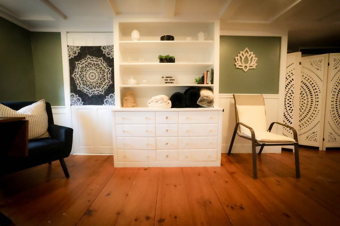A living room with hardwood floors , a chair and a dresser.