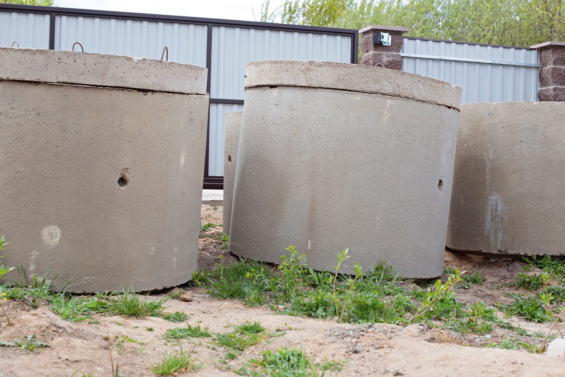 Three concrete rings are sitting on top of a dirt field