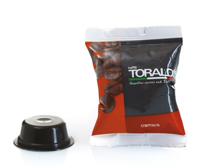 Cialda e bustina di caffè, cialda nera a sinistra, bustina rossa e nera sigillata a destra con chicchi di caffè.