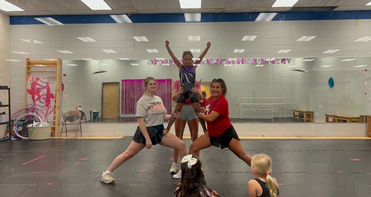 A group of cheerleaders are practicing in a gym.
