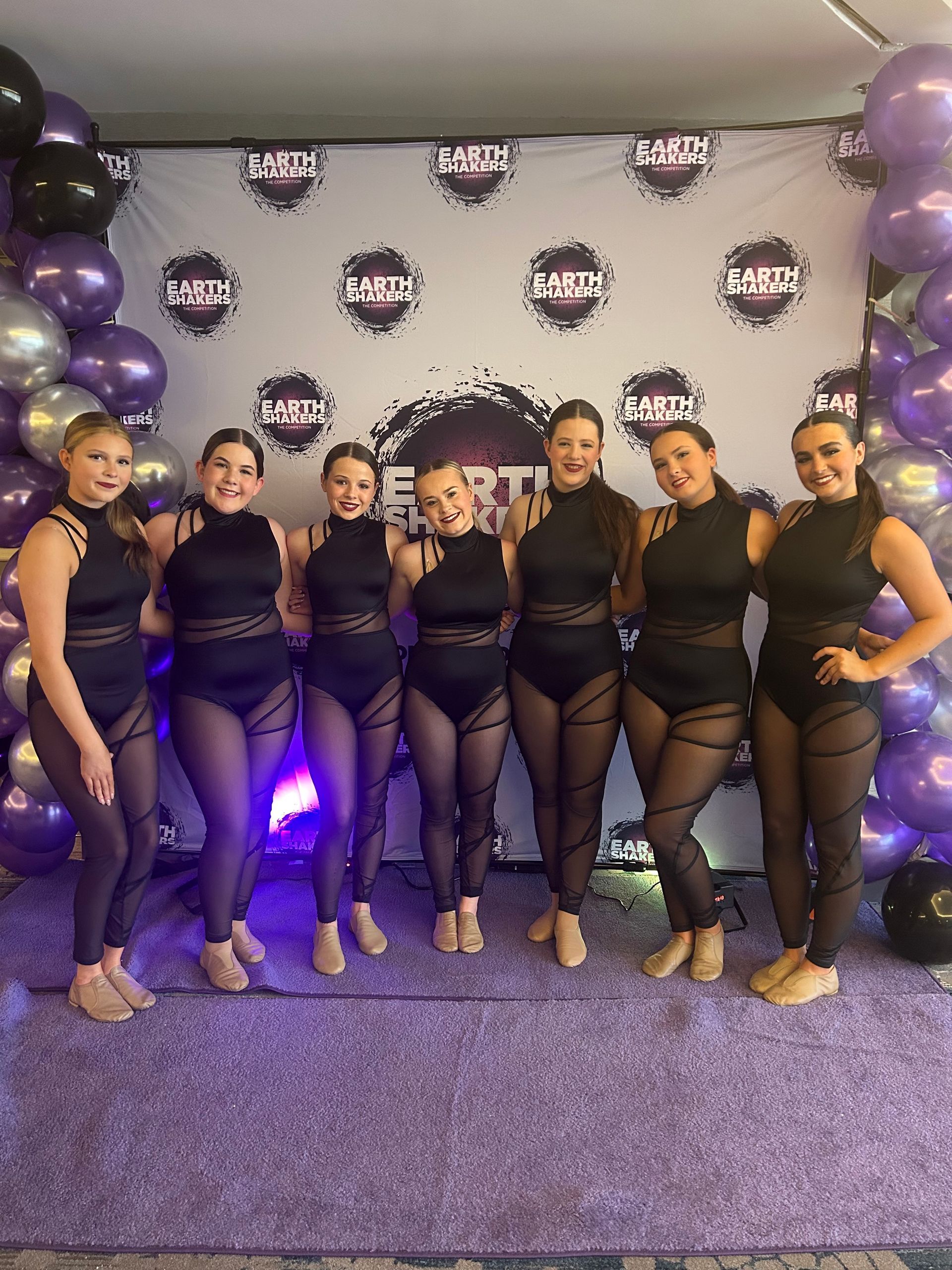A group of women are posing for a picture in front of balloons.