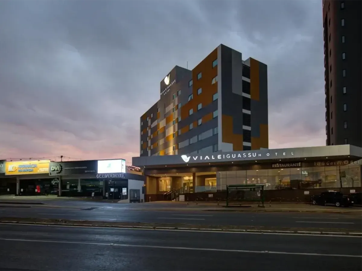 Hotel com fachada laranja e cinza ao entardecer.