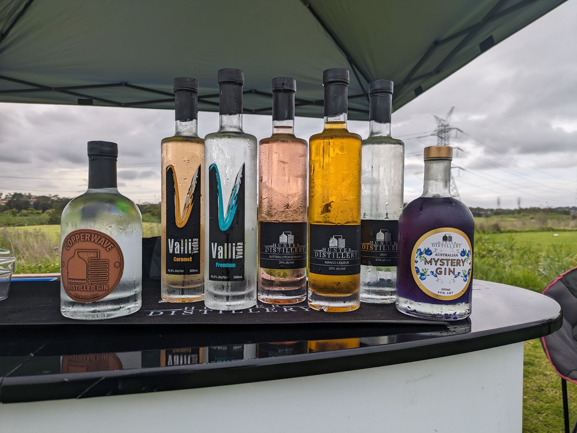 A row of bottles sitting on top of a table under a tent.