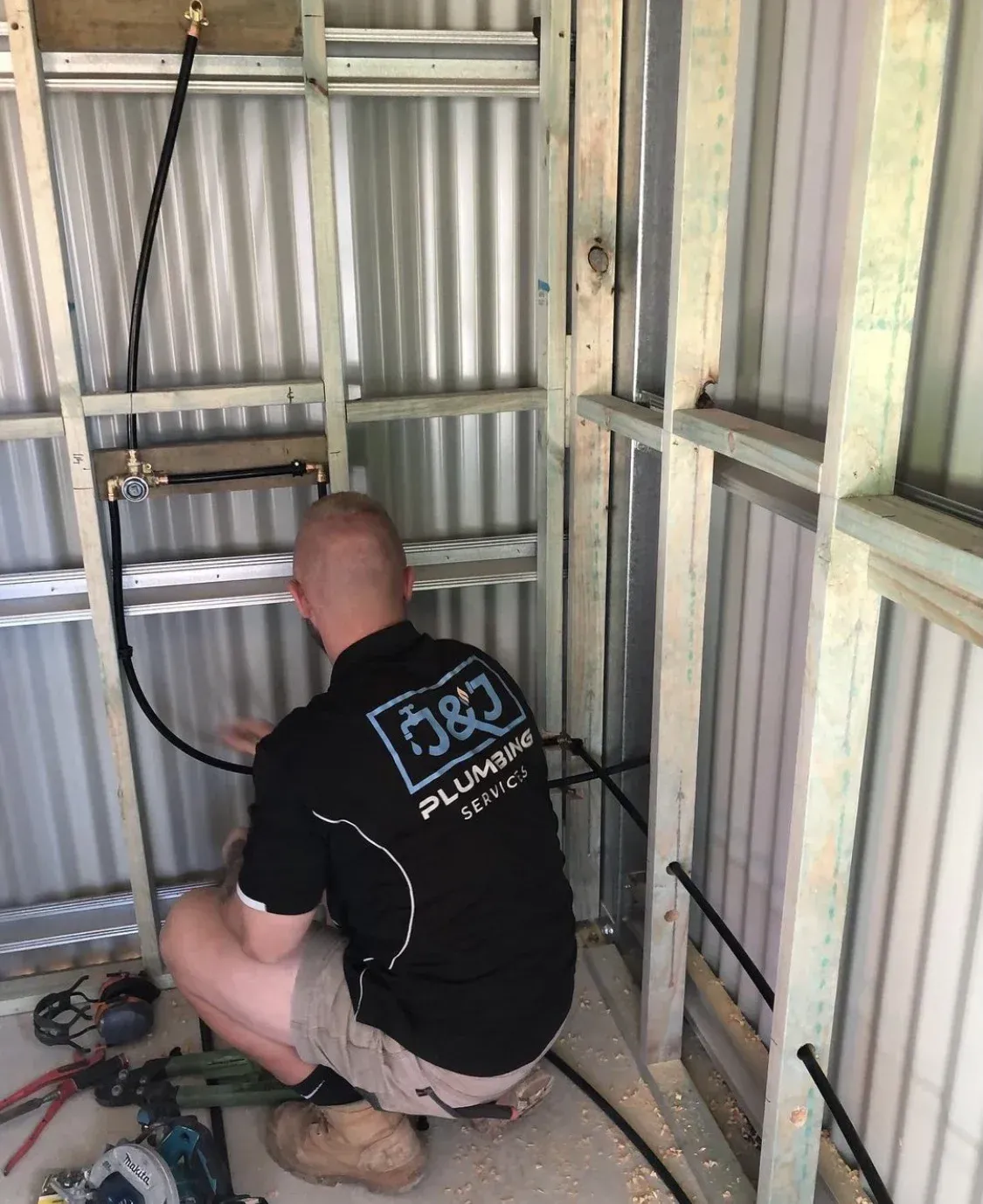 A man is kneeling down in a room working on a pipe.