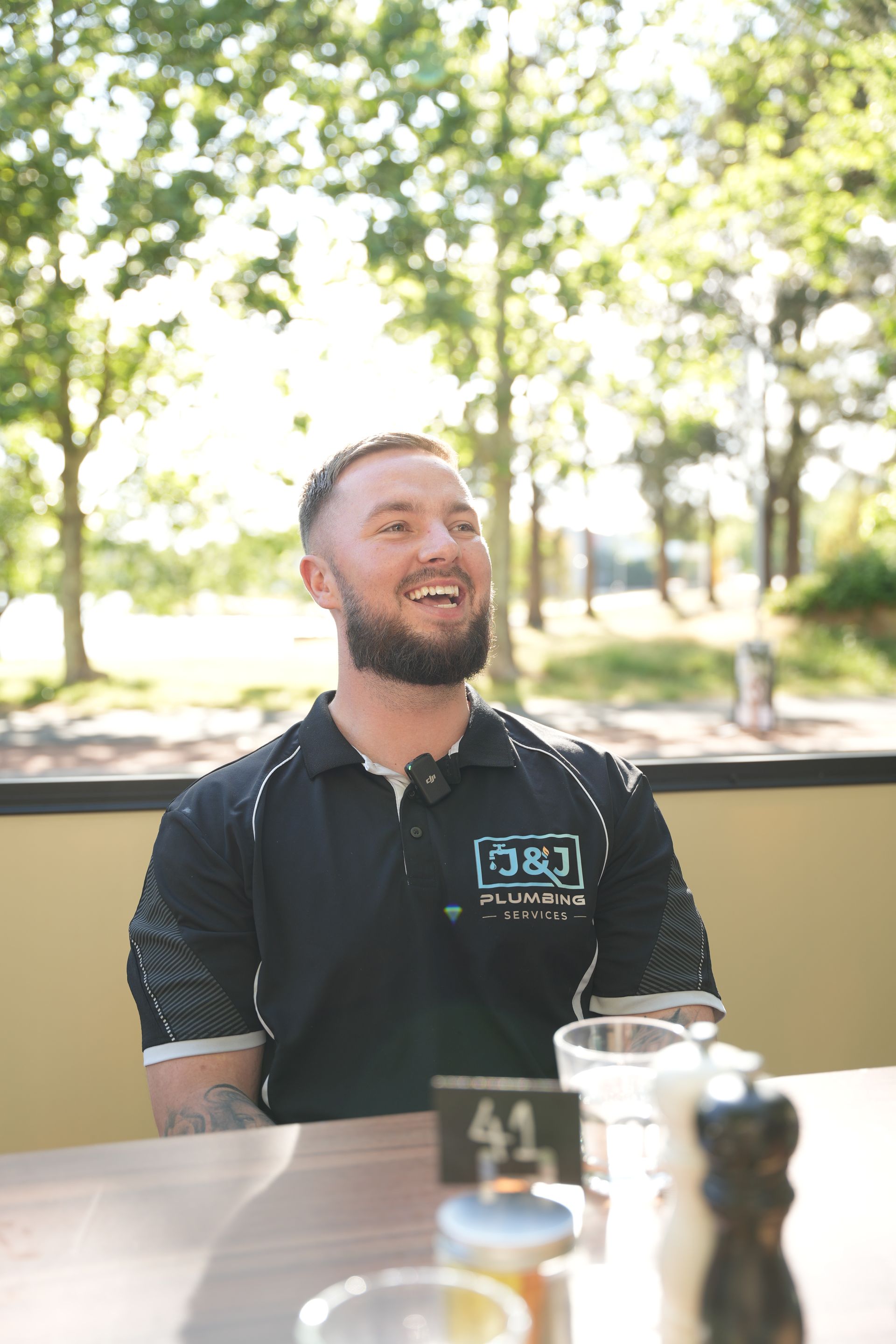 A man wearing a j & j plumbing hoodie is working on a pipe