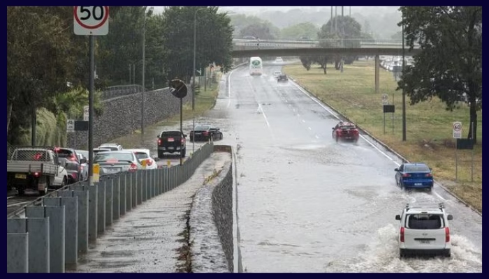 Flash flooding on a Canberra road after heavy rain, cars navigating through stormwater