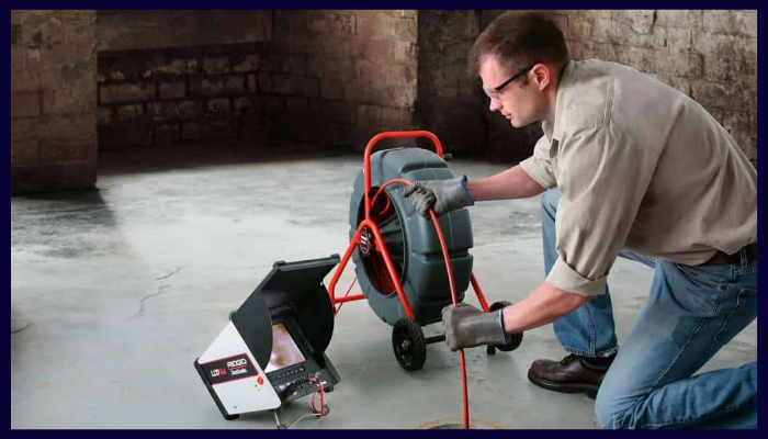 Plumber using a CCTV drain camera to diagnose a blocked pipe