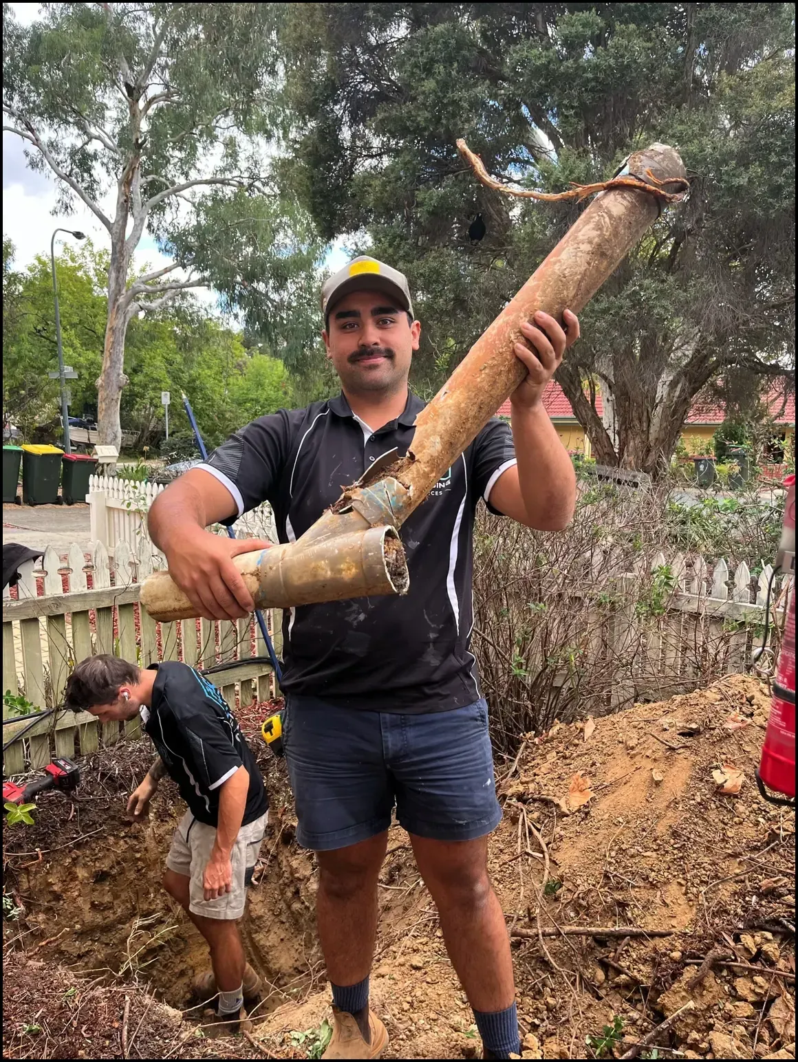 Emergency plumber holding a leaking pipe inside a Canberra home during an urgent plumbing repair