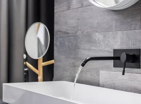 A bathroom sink with a black faucet and a mirror.