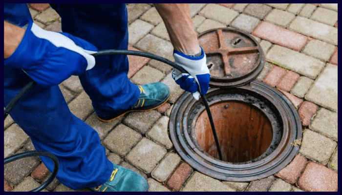 Professional plumber using a hydro-jetting hose to clear a blocked outdoor drain in a Canberra home