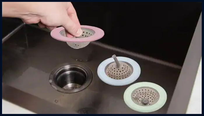 Person placing a sink strainer into a kitchen drain to prevent blockages from food and debris