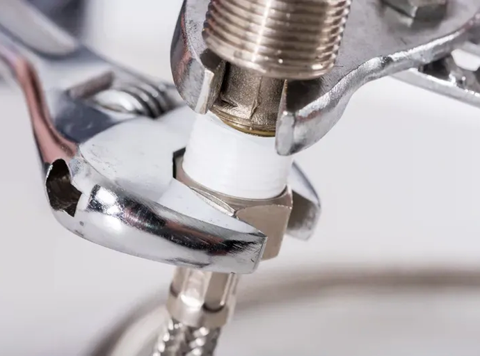 A wrench is being used to fix a pipe.