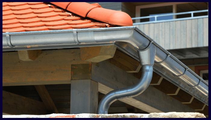 metal gutter and downpipe system installed on a house roof